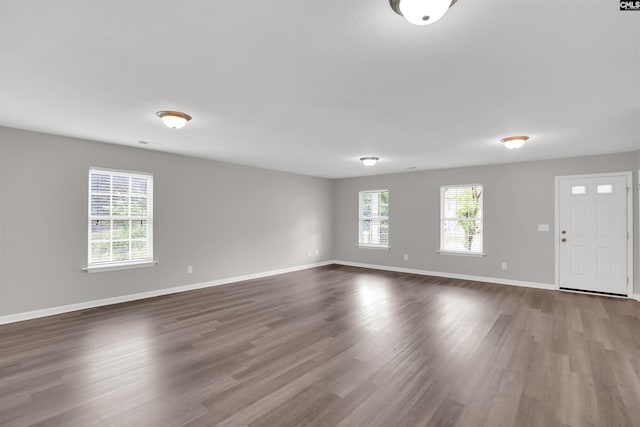 interior space featuring baseboards, a healthy amount of sunlight, and dark wood-type flooring