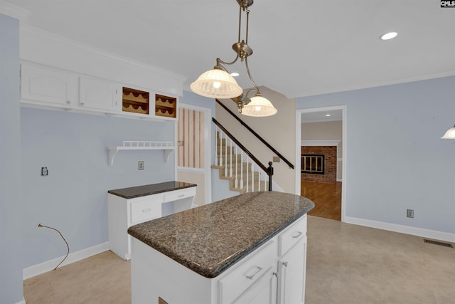 kitchen featuring a brick fireplace, visible vents, baseboards, white cabinetry, and pendant lighting