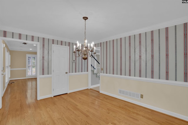 unfurnished dining area with wood finished floors, baseboards, visible vents, a notable chandelier, and crown molding