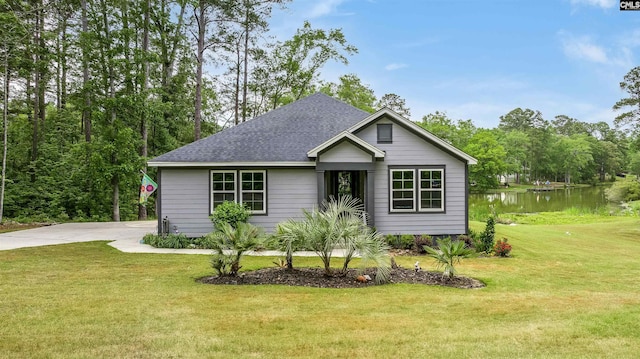 view of front of property featuring a front yard, a water view, and roof with shingles