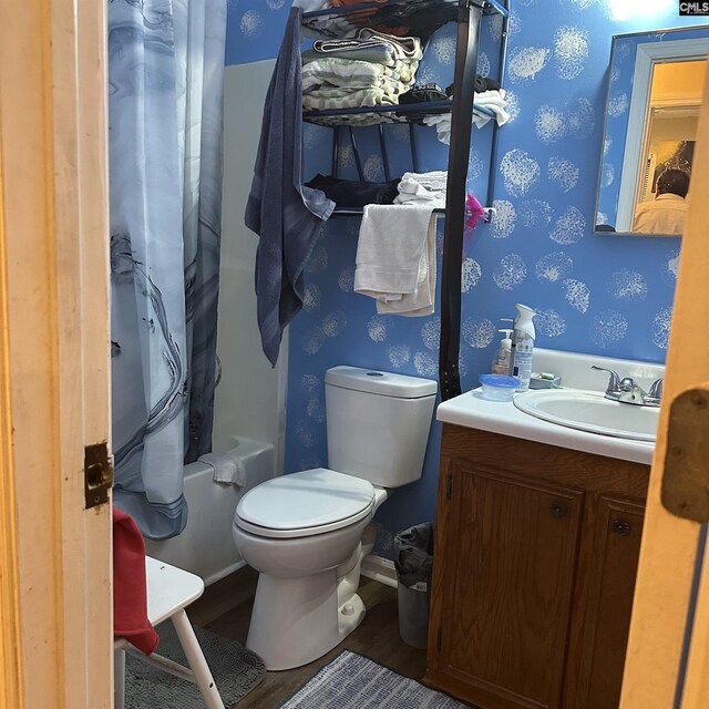 full bath with shower / bath combo, vanity, toilet, wallpapered walls, and wood finished floors