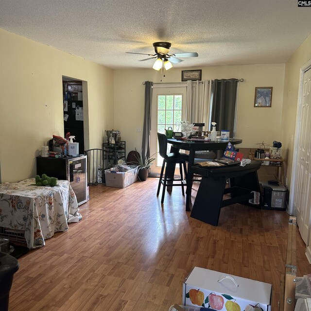 dining space featuring a ceiling fan, wood finished floors, and a textured ceiling