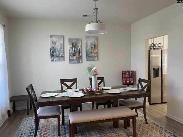 dining area with baseboards, visible vents, and wood finished floors