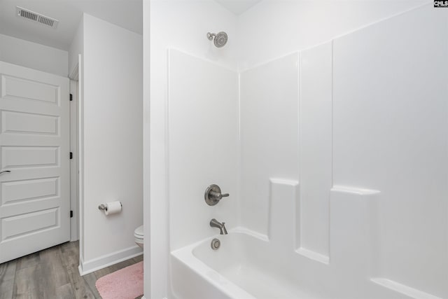 full bath featuring toilet, visible vents, bathtub / shower combination, baseboards, and wood finished floors