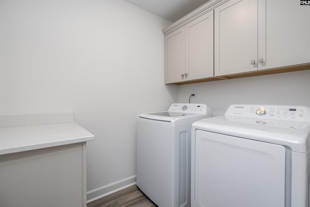 laundry room featuring wood finished floors, baseboards, cabinet space, and washing machine and dryer