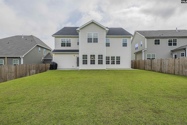 rear view of house with a lawn and a fenced backyard