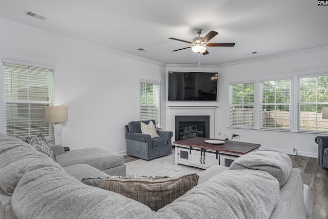 living area with ornamental molding, a ceiling fan, visible vents, and wood finished floors