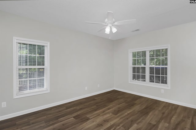 spare room with dark wood-type flooring, plenty of natural light, and baseboards