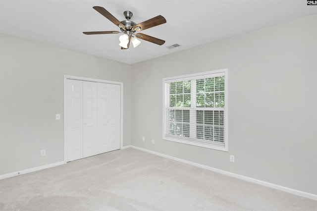 unfurnished bedroom with baseboards, visible vents, a closet, and light colored carpet