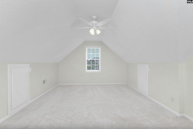 additional living space featuring a textured ceiling, light colored carpet, and baseboards