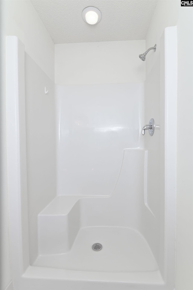 bathroom with a textured ceiling and walk in shower