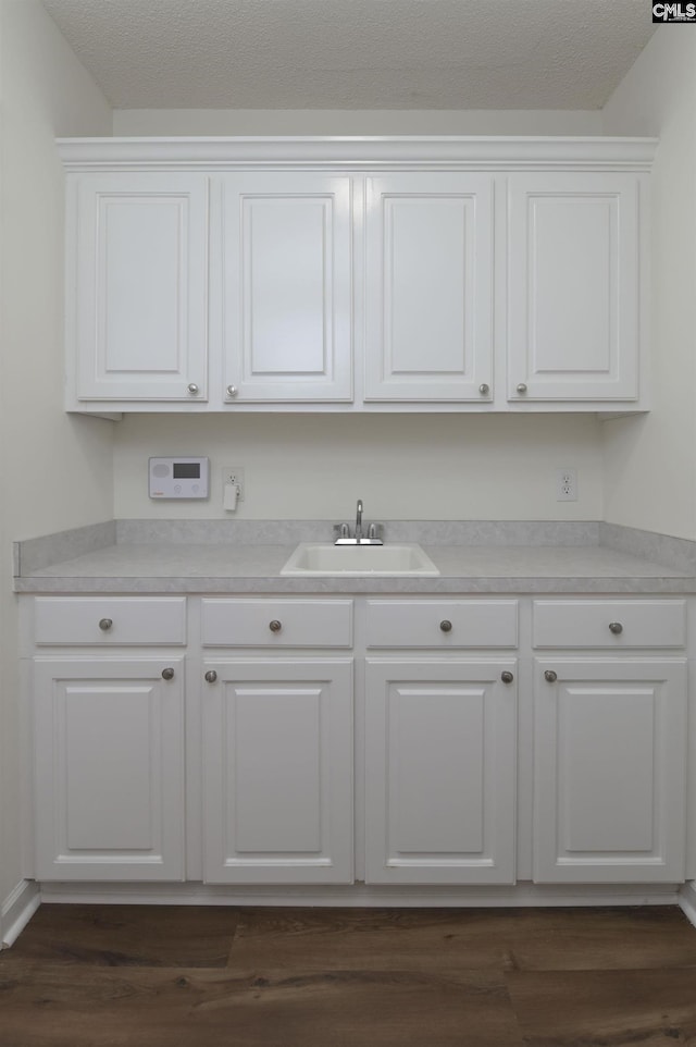 kitchen with light countertops, white cabinets, dark wood finished floors, and a sink