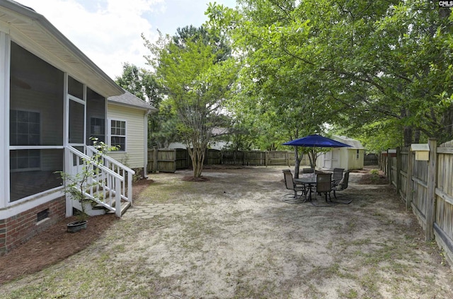view of yard with an outdoor structure, a sunroom, a storage unit, and a fenced backyard