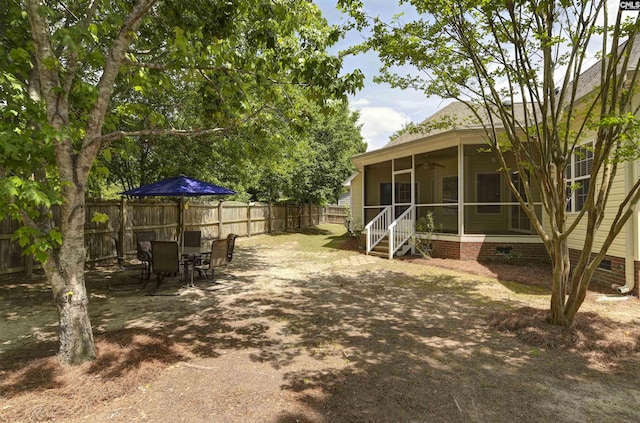view of yard featuring ceiling fan, a sunroom, and a fenced backyard