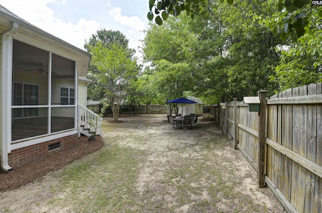 view of yard with a patio, outdoor dining space, a sunroom, and a fenced backyard