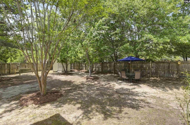 view of yard with a storage unit, an outdoor structure, and a fenced backyard