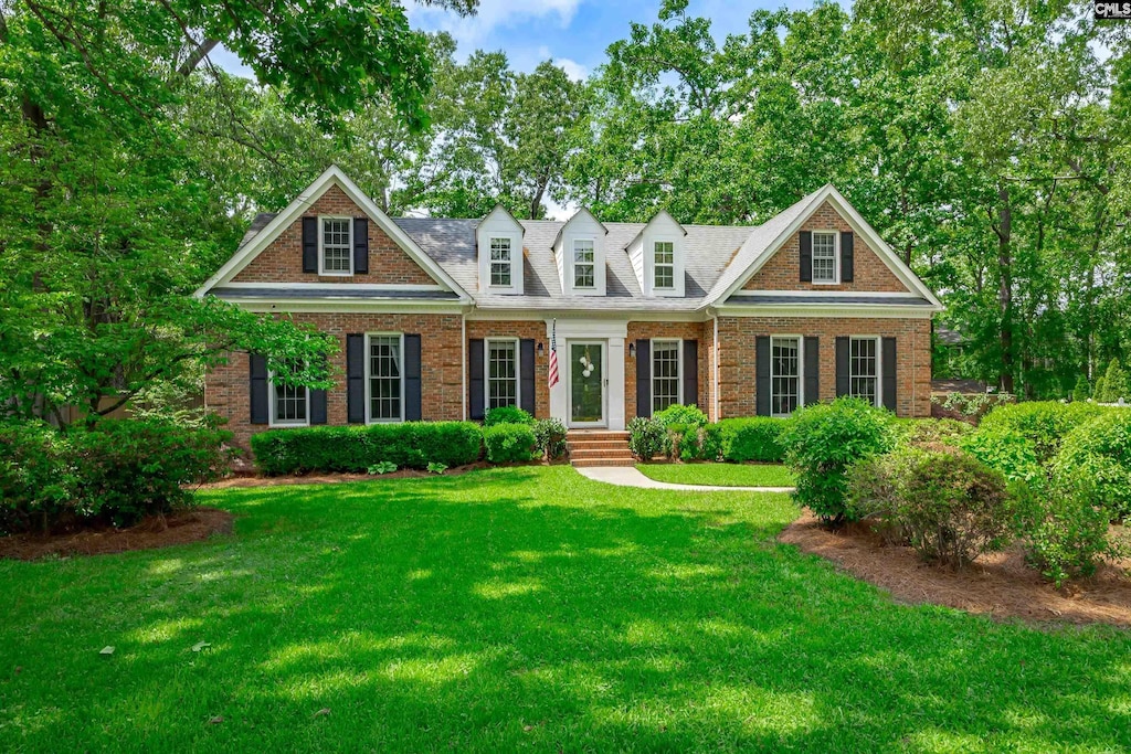 cape cod-style house featuring brick siding and a front lawn