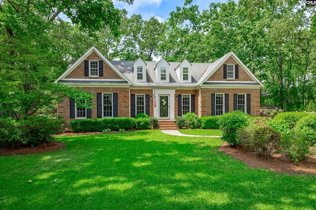 cape cod-style house featuring brick siding and a front lawn