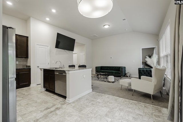 kitchen with light stone countertops, stainless steel appliances, a sink, open floor plan, and lofted ceiling