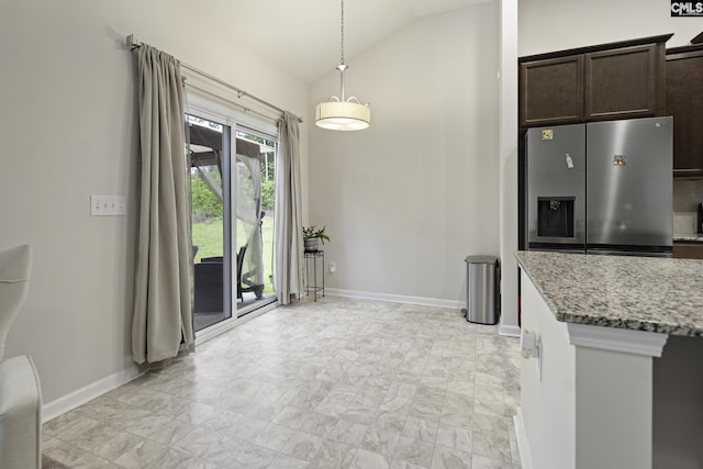 kitchen featuring light stone countertops, vaulted ceiling, dark brown cabinets, baseboards, and stainless steel refrigerator with ice dispenser