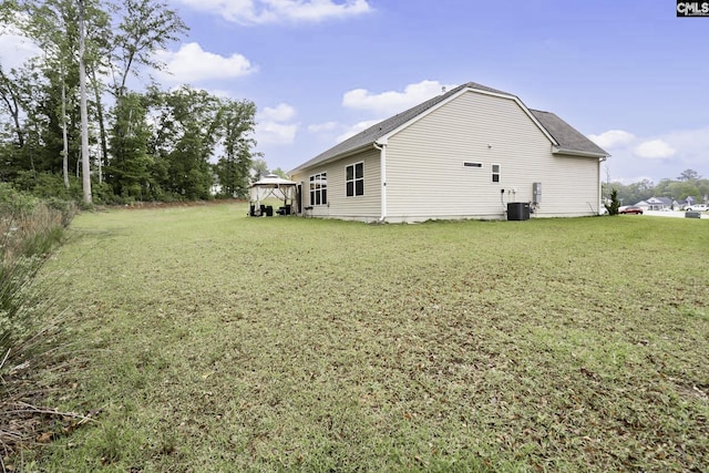 view of side of home with central air condition unit, a yard, and a gazebo