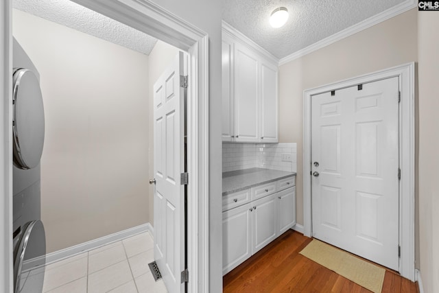 257 Popes Ln, Lexington, SC 29072 - clothes washing area featuring a textured ceiling, estacked washer and dryer, cabinet space, crown molding, and baseboards