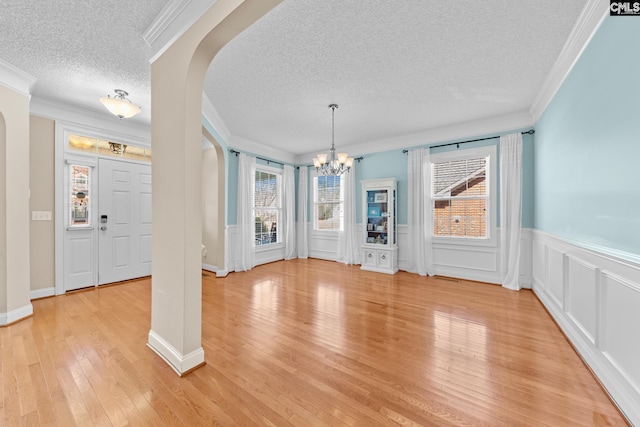 257 Popes Ln, Lexington, SC 29072 - unfurnished dining area featuring a textured ceiling, arched walkways, a chandelier, crown molding, and light wood-type flooring