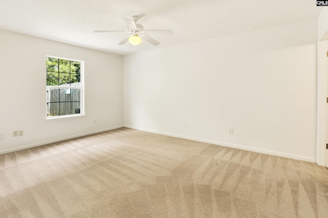 empty room featuring ceiling fan, light colored carpet, and baseboards