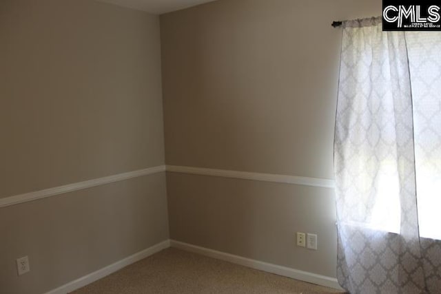 unfurnished room featuring carpet and baseboards