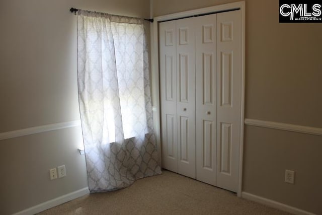 unfurnished bedroom featuring carpet, baseboards, and a closet