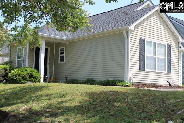 view of home's exterior with a shingled roof and a lawn