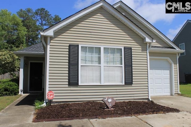 view of front facade with concrete driveway, a garage, and central AC