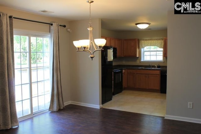 kitchen featuring an inviting chandelier, black appliances, dark countertops, a sink, and baseboards