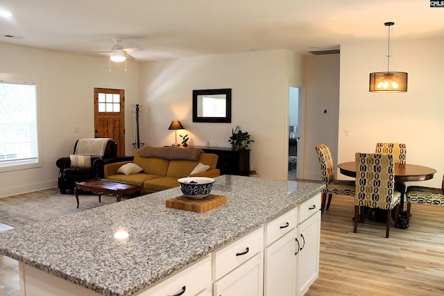 kitchen featuring a ceiling fan, visible vents, light stone counters, light wood-style flooring, and white cabinetry