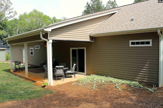 back of house with a lawn, a patio area, and a shingled roof