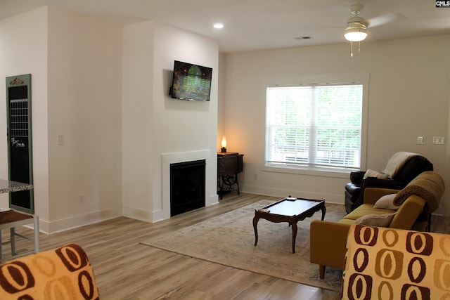 living room featuring visible vents, a ceiling fan, light wood-style floors, and a heating unit