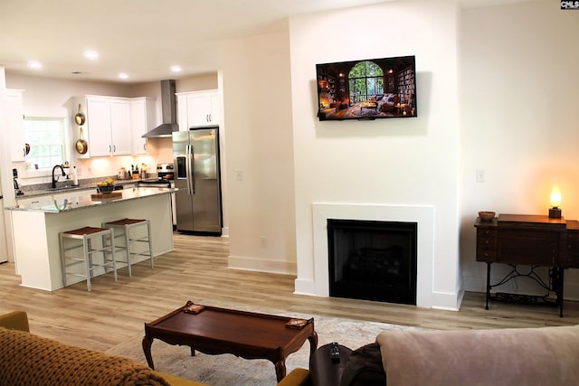 living room featuring a fireplace, light wood finished floors, recessed lighting, and baseboards