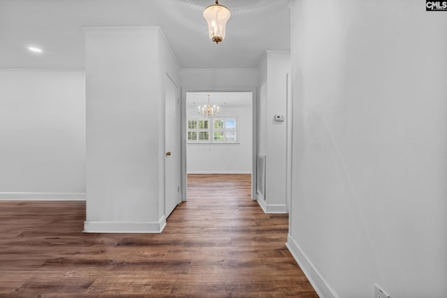 hallway featuring an inviting chandelier, crown molding, visible vents, baseboards, and dark wood finished floors