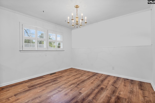 unfurnished room featuring baseboards, wood finished floors, a notable chandelier, and crown molding