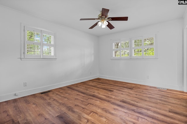 unfurnished room with wood finished floors, visible vents, a ceiling fan, and baseboards