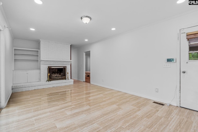 unfurnished living room with crown molding, recessed lighting, visible vents, and a brick fireplace