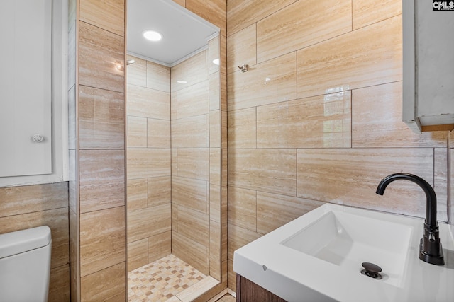full bathroom featuring tile walls, toilet, a tile shower, and vanity