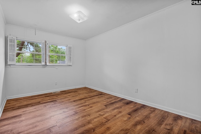 empty room featuring ornamental molding, wood finished floors, and baseboards