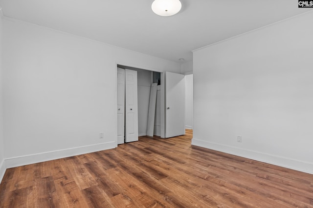 spare room featuring crown molding, wood finished floors, and baseboards