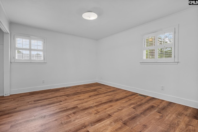 spare room with visible vents, wood finished floors, and baseboards
