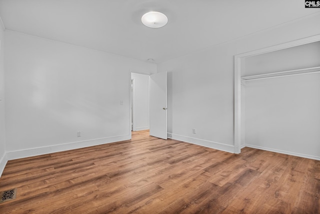 unfurnished bedroom featuring a closet, visible vents, light wood-style flooring, and baseboards