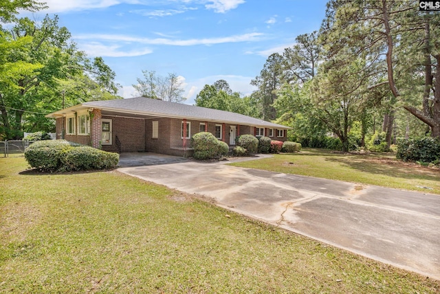 ranch-style home with brick siding, fence, an attached carport, driveway, and a front yard