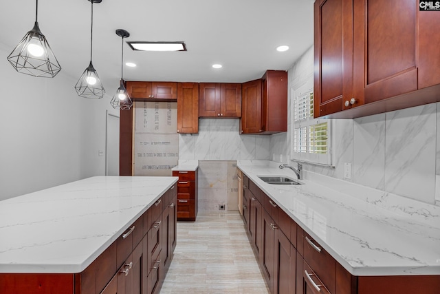kitchen with recessed lighting, light stone countertops, a sink, a kitchen island, and hanging light fixtures