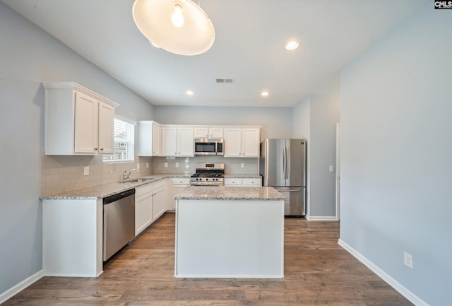 kitchen with a sink, white cabinets, stainless steel appliances, and decorative backsplash