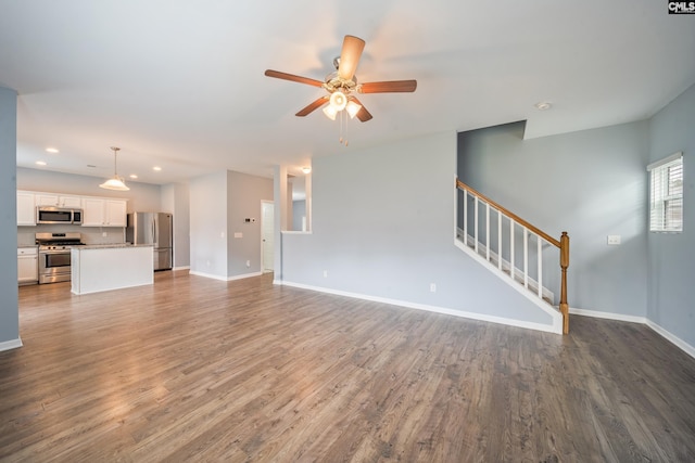 unfurnished living room featuring a ceiling fan, dark wood-style floors, stairs, and baseboards